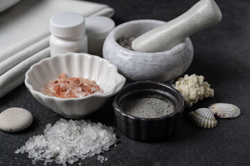 Crystals of white, gray, pink salt and sea mineral powder in bowls and in mortar