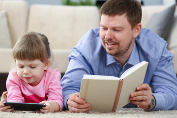 Father reading book to daughter while child stare at smartphone