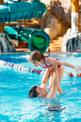 Naklejka premium dad and daughter have fun and play in the pool. swimming training. 