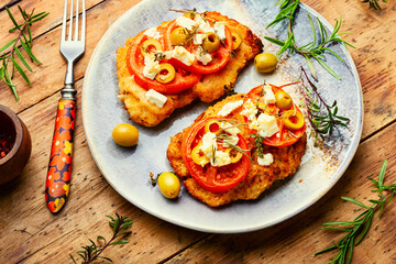 Fried schnitzel with olives and tomato