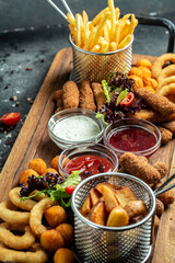 fast food meals mozzarella sticks, onion rings, french fries, chicken nuggets and sauce. pub...