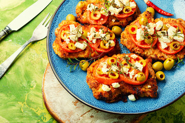 Meat schnitzel with cheese, olives and tomato