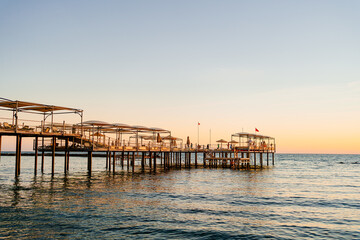 Fototapeta premium pier with umbrellas and sunbeds on the evening. beautiful sunset on sea. 