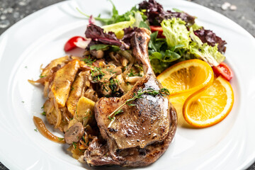 duck leg confit meat portion of prepared with baked potatoes, mushrooms and onions, top view