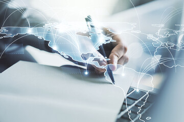 Double exposure of abstract digital world map with connections and hand writing in notepad on background with laptop, big data and blockchain concept