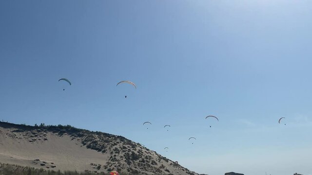 Static view of parashoots floating in sky. Dune de Pilat, Arcachon. France