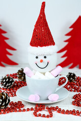 Snowman and marshmallows in cup, red felt christmas tree on white background.