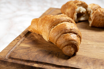 Closeup of tasty croissants with caramel fillling on the wooden board