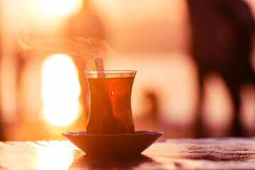 Traditional Turkish tea in a glass against the background of sunrise lights near Bosphorus