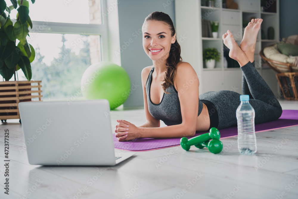 Sticker portrait of attractive cheerful girl lying on carpet doing physical development watching web instruc