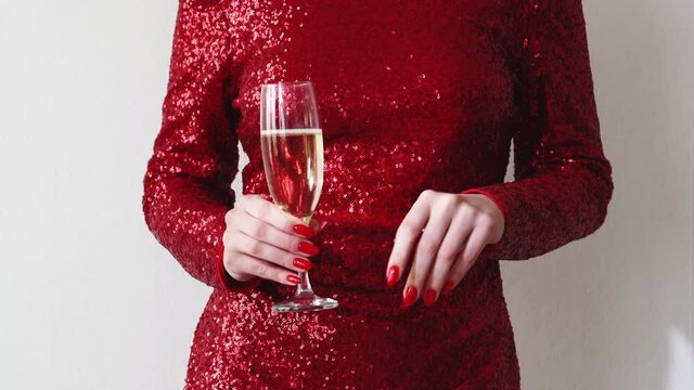 Party toast. Womans day. Festive celebration. Unrecognizable happy elegant lady in red paillette dress dancing with champagne glass isolated white copy space.