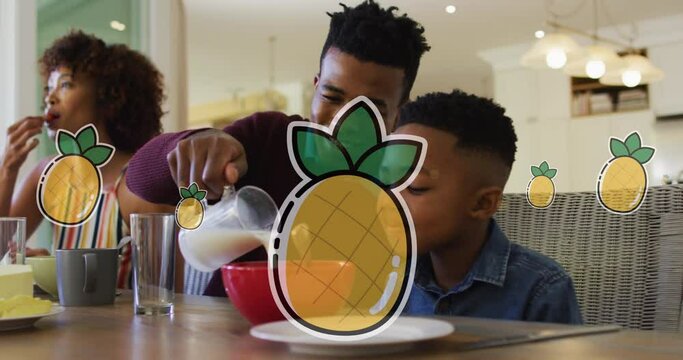 Animation of pineapples over happy african american parents and son having breakfast at home
