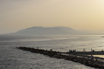 People on breakwater at sunset
