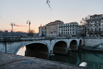 A bridge in Rome at sunset. Tevere river flows under it.
