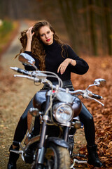 Plakat A beautiful woman with long hair on a chopper motorcycle in autumn landscape.