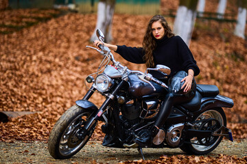 Obraz na płótnie Canvas A beautiful woman with long hair on a chopper motorcycle in autumn landscape.
