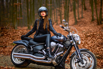 Naklejka na ściany i meble A beautiful woman with long hair on a chopper motorcycle in autumn landscape.