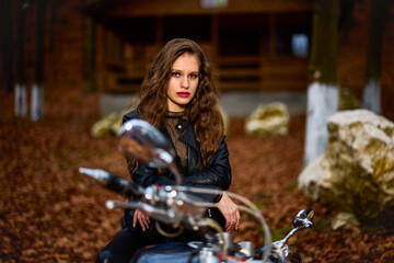 Obraz na płótnie Canvas A beautiful woman with long hair on a chopper motorcycle in autumn landscape.