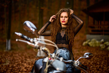 Plakat A beautiful woman with long hair on a chopper motorcycle in autumn landscape.