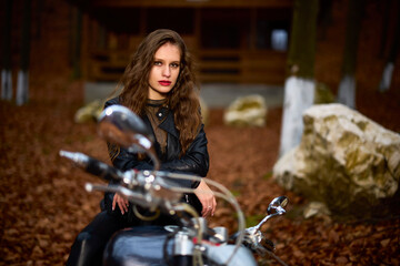 A beautiful woman with long hair on a chopper motorcycle in autumn landscape.