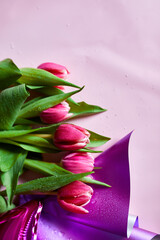 Top view pink tulips flowers in violet paper wrapper, festive background, concept of Happy Mother's day, Woman's day, birthday, 8 March, Valentines day