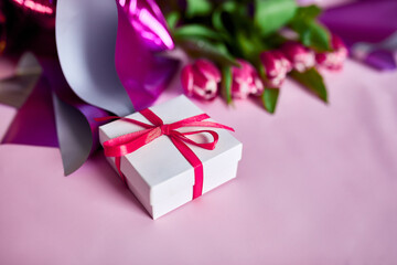 Top view pink tulips flowers in violet paper wrapper with gift box, festive background, concept of Happy Mother's day, Woman's day, birthday, 8 March, Valentines day