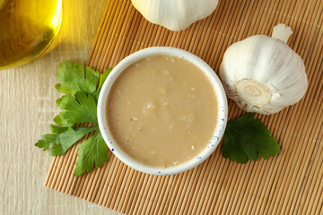 Concept of tasty food with tahini sauce on light wooden background