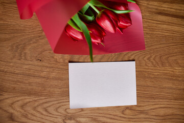 Top view empty card with  red tulips flowers in red paper wrapper with gift box, festive background, concept of Happy Mother's day, Woman's day, birthday, 8 March, Valentines day