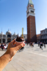 Hand handling a chocolate ice cream at the Piazza San Marco (Saint Mark square) in Venezia, Veneto, Italy.