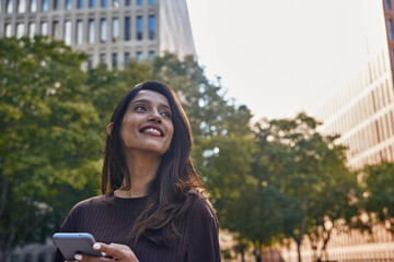 Fototapeta premium Smiling businesswoman with mobile phone on street