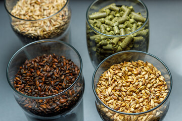 Malt for light and dark beer, hops in granules in glass glasses.
