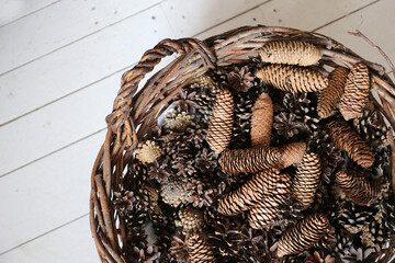 wicker basket with pine cones on white wooden floor