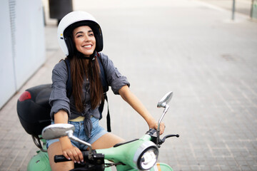 Beautiful woman getting ready for a ride on scooter. Beautiful happy lady having fun outdoors..