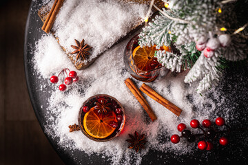 Cozy atmosphere with glass of Mulled wine, Christmas winter alcohol drink decorated by snow and christmas lights