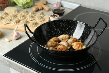 Cooking gyoza on frying pan with hot oil in kitchen