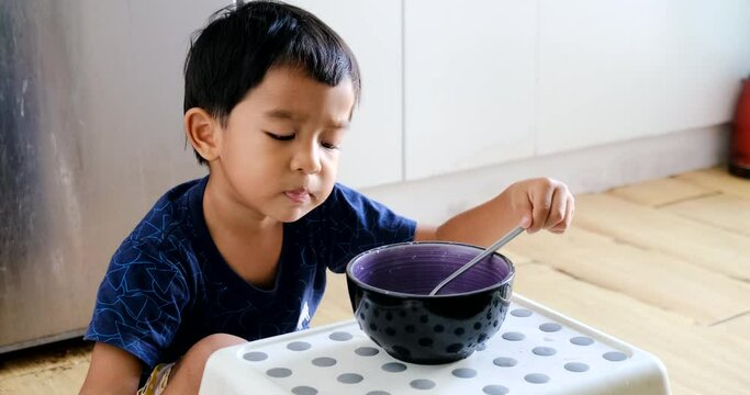 Adorbale little boy enjoy eating breakfast asin local food in house