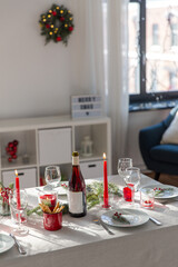 winter holidays, dinner party and celebration concept - christmas table serving with candles, crockery and wine at home