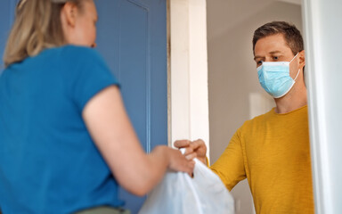 Fototapeta premium Masked man delivers food during pandemic.