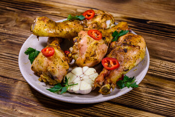 Baked chicken legs with parsley, garlic and sliced red hot pepper in a plate