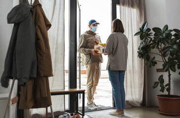 food shipping, pandemic and people concept - delivery man in mask giving order in wooden box to female customer at home