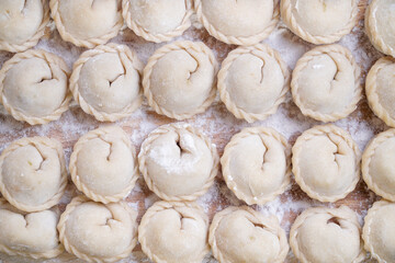 Meat or vegeterian dumplings, pelmeni on a wooden board. Russian national food. Close up top view.