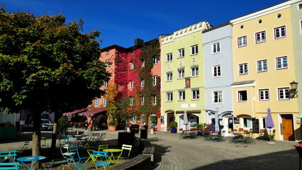 schöne Innenstadt von Wasserburg am Inn mit bunten Häusern, Bäumen und Biergarten unter blauem Himmel