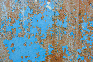 Peeling paint on the wall. Old concrete wall with cracked flaking paint. Weathered rough painted surface with patterns of cracks and peeling. Grunge texture for background and design. High resolution.