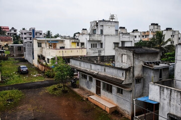 Obraz premium Roof top view of residential group housing , apartment and bungalows in the urban area, picture captured during rainy season with dark clouds. Parked vehicles outside of the houses at Kolhapur, India.