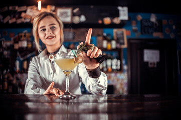 Professional girl bartending demonstrates his professional skills while standing near the bar counter in bar