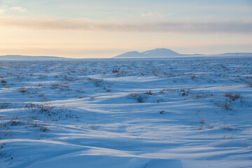 View of the snow-covered tundra and snow-capped mountains. Winter arctic landscape. Cold frosty winter weather. Arctic desert. Northern nature of polar Siberia and Chukotka. The Far North of Russia.