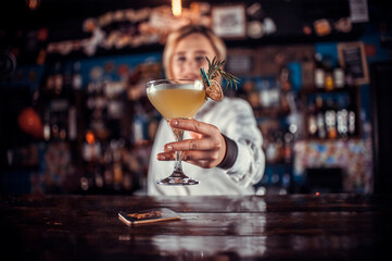 Portrait of woman mixologist formulates a cocktail at the bar counter