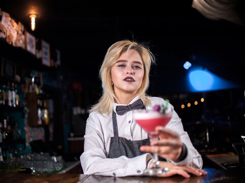 Young girl bartender demonstrates the process of making a cocktail