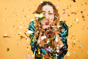 Happy crazy girl blowing confetti with yellow background - Focus on arms