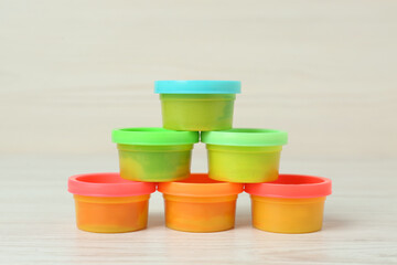 Plastic containers with colorful play dough on white wooden table